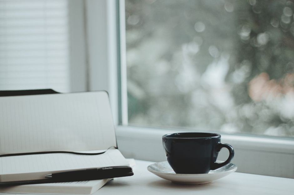 A serene scene with a coffee cup and notebook by a window, perfect for calm mornings.