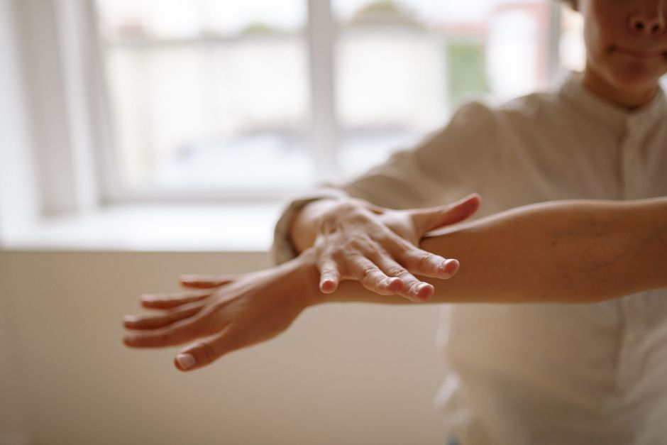 A close-up view of a person using a relaxation technique with hands in motion, in a bright, airy space.