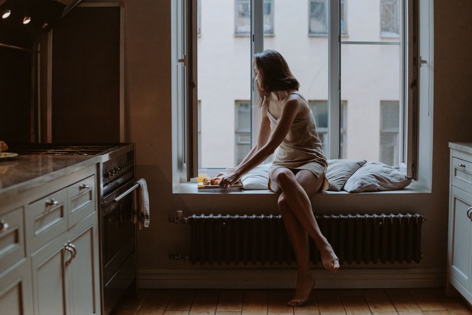 A serene scene of a woman sitting by the window in a cozy kitchen, enjoying a calm moment.