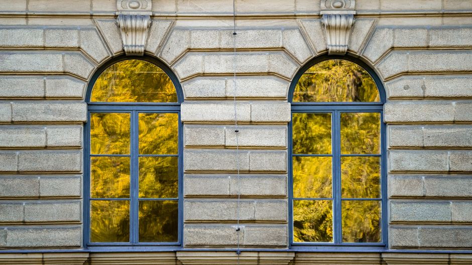 Close-up of arched windows reflecting bright autumn foliage in Erlangen, Germany.