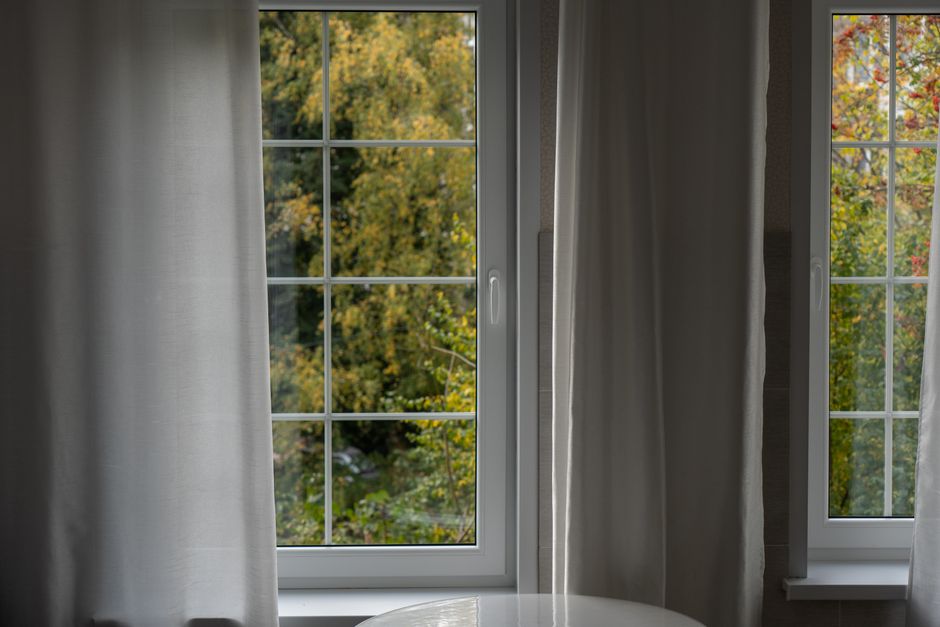 Serene interior with white curtains framing a lush green outdoor view through a window.